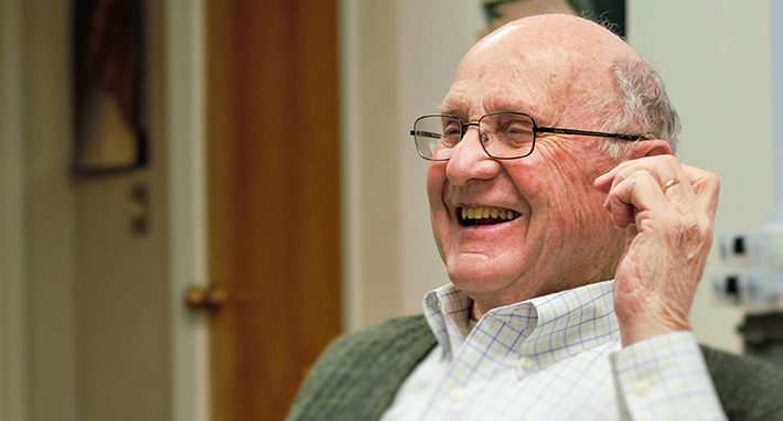 An elderly gentleman grins as he regains his hearing for the first time in years due to properly customized hearing aids